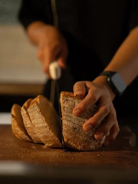 Tangan mengiris roti sourdough hangat